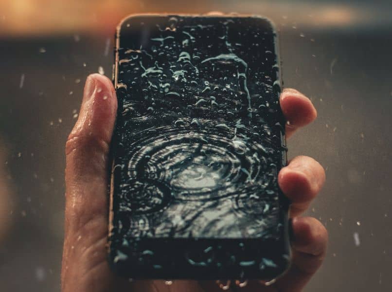 telefono movil negro mojado en mano