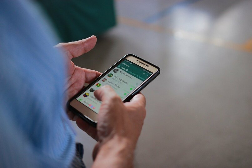 persona sosteniendo su dispositivo movil con whatsapp en su pantalla
