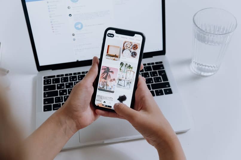 viendo imagenes en un movil con una laptop sobre una mesa