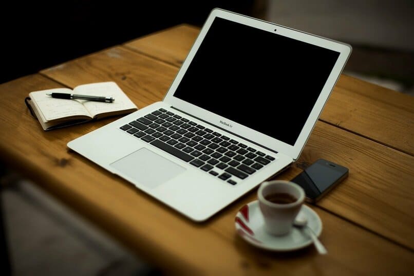 laptop junto una taza de cafe