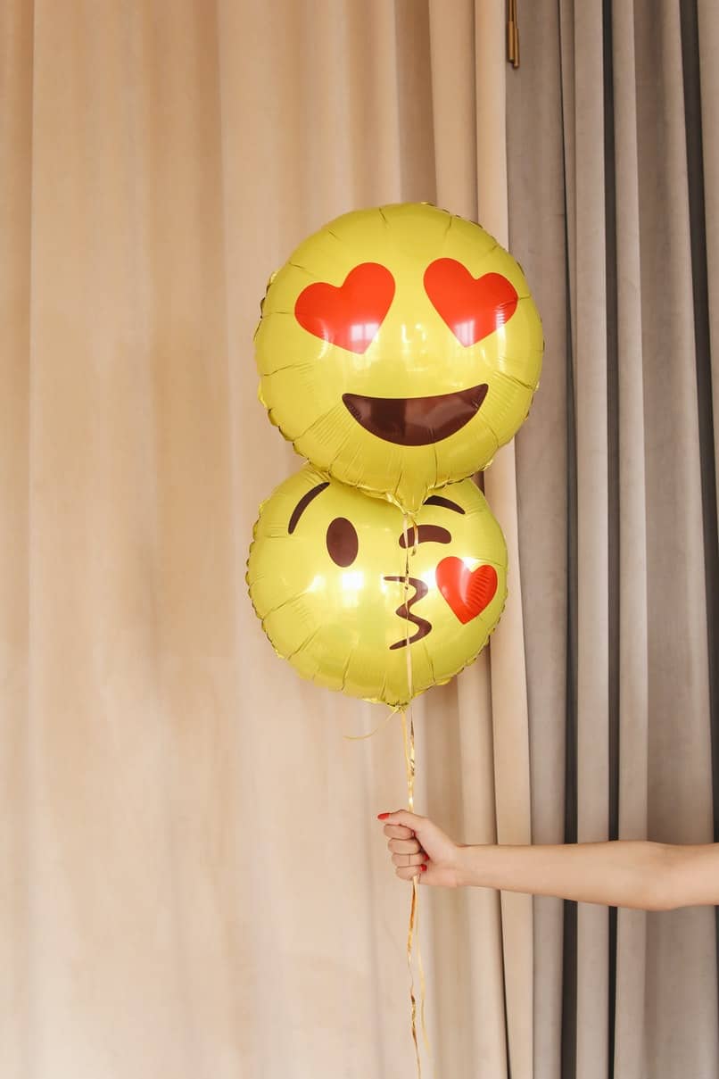 chica sosteniendo globos de emojis