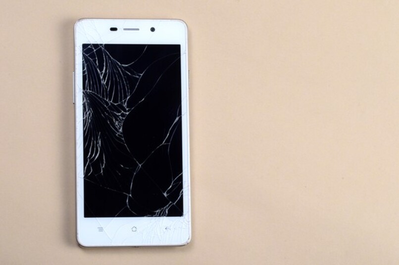 telefono blanco con la pantalla partida sobre mesa marron