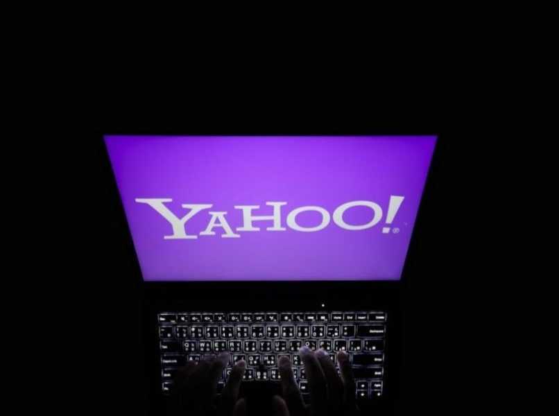 laptop negra con logo de yahoo fondo oscuro