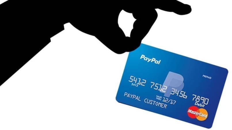 mano color negro sosteniendo una tarjeta paypal
