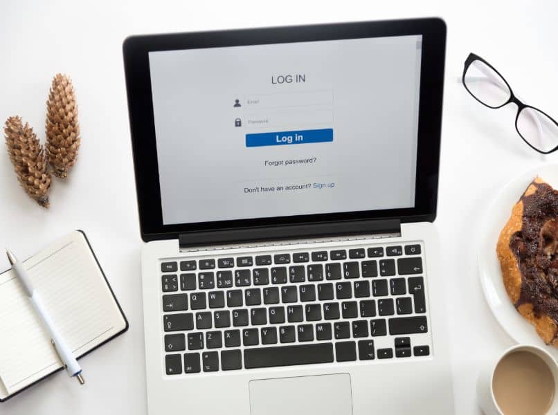 laptop con usuario y clave mesa blanca lentes y libreta