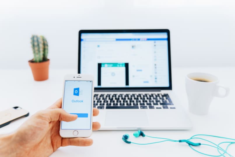 persona utilizando facebook en portatil y outlook en el movil